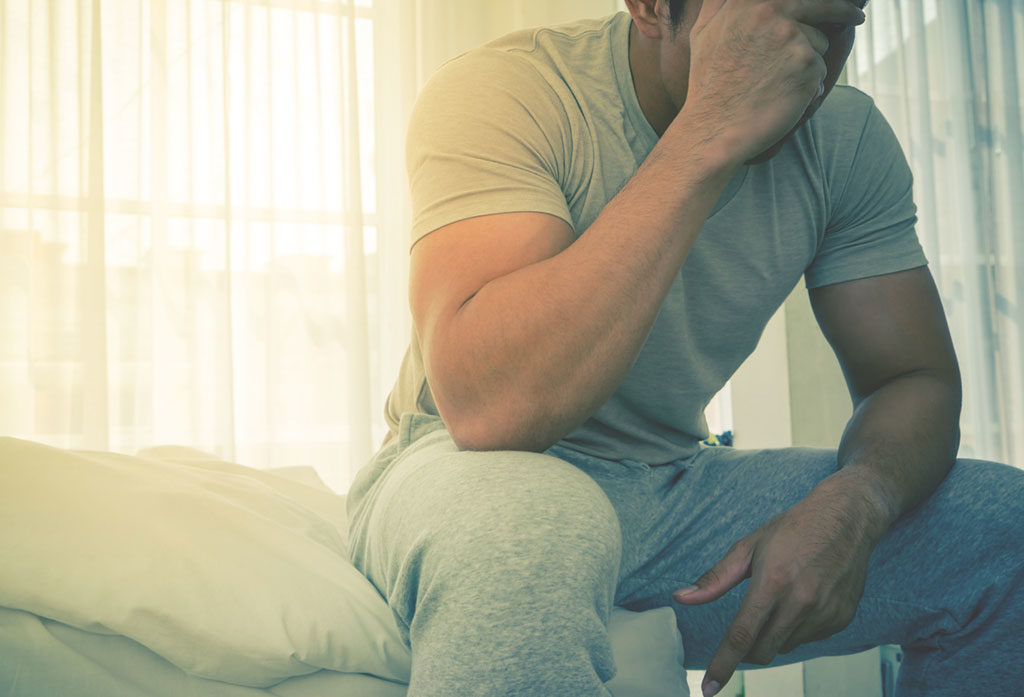 worried man sitting on bed